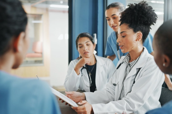 Une photographie de plusieurs professionnels de la santé discutant du contenu d’une tablette.