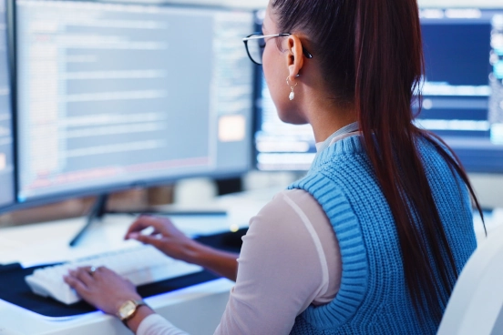 Une photographie d’une personne assise devant un écran d’ordinateur en train de taper
