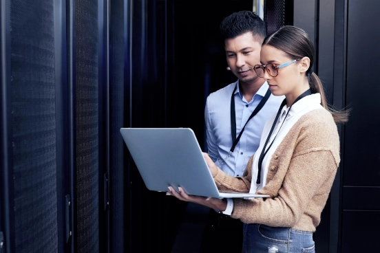 Une image de deux personnes discutant du contenu d’un écran d’ordinateur portable à l’intérieur d’un centre de données.