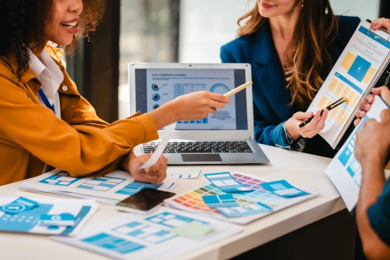 A photograph of three people reviewing colour swatches and design elements of a web site. 
